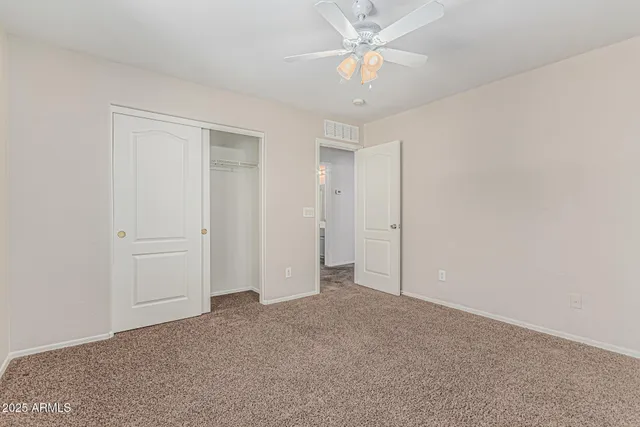 an empty room with a chandelier fan and windows
