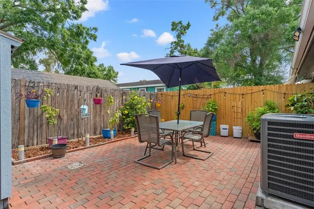 a view of a patio with a table and chairs under an umbrella with a barbeque