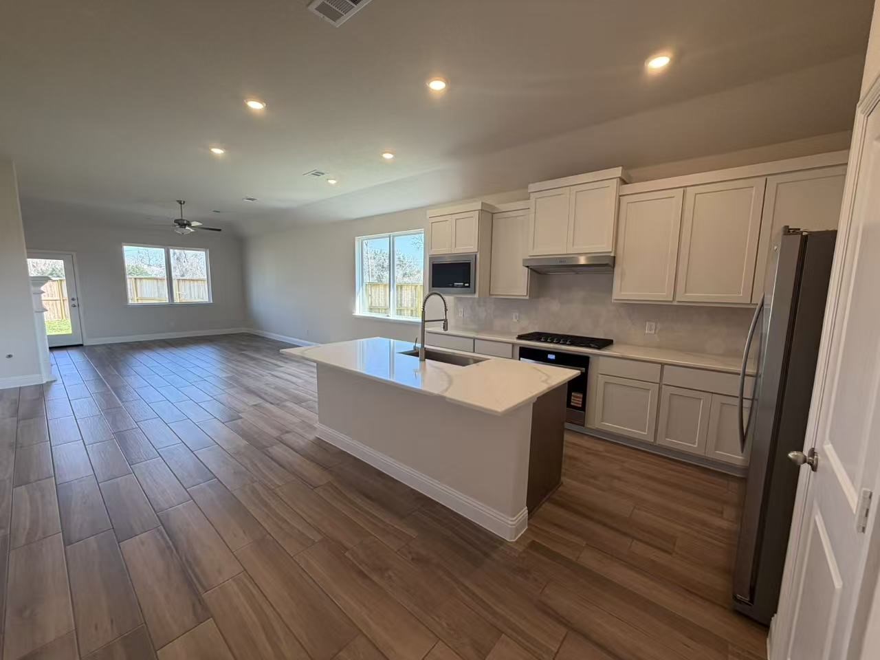 4014 Colony Lane Missouri City, TX 77459 - Photo 16 of 40 a large kitchen with kitchen island wooden floors white cabinets and stainless steel appliances