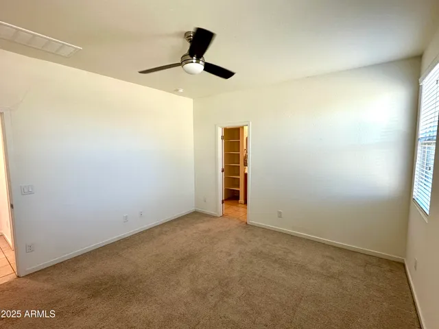 an empty room with a ceiling fan and carpet