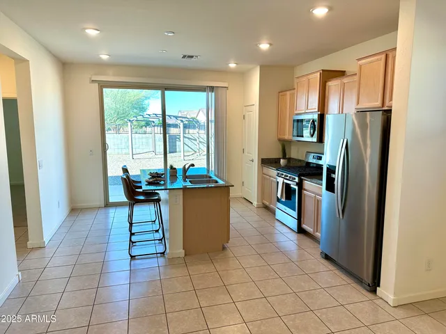 a kitchen with stainless steel appliances kitchen island granite countertop a refrigerator a stove and a sink