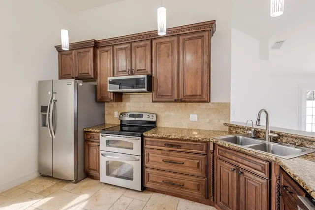 a kitchen with stainless steel appliances granite countertop a refrigerator stove and sink