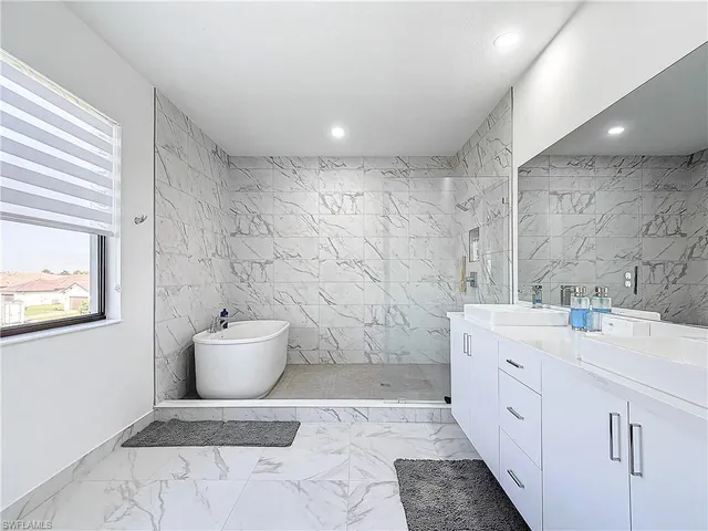 a spacious bathroom with a double vanity sink a toilet a mirror and shower