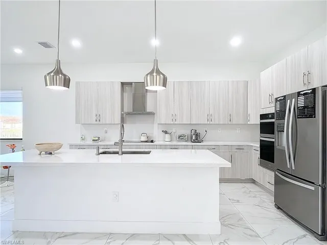 a kitchen with stainless steel appliances granite countertop a sink a stove a refrigerator and island with wooden floor