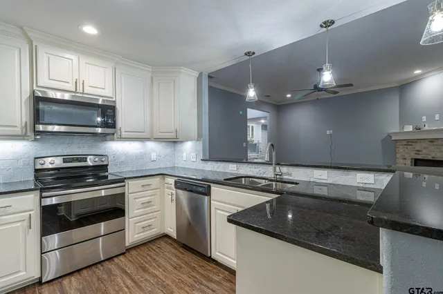 a kitchen with stainless steel appliances granite countertop a sink a stove and cabinets