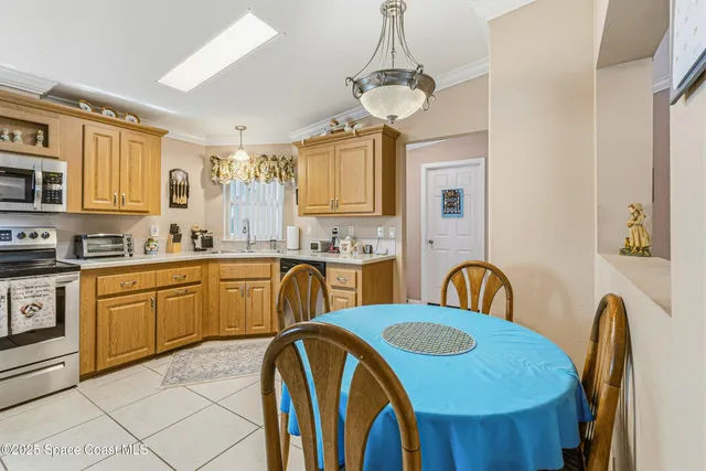 a kitchen with stainless steel appliances a sink a stove a refrigerator cabinets and a dining table