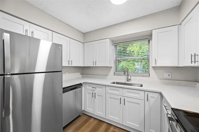 a kitchen with white cabinets white stainless steel appliances and sink