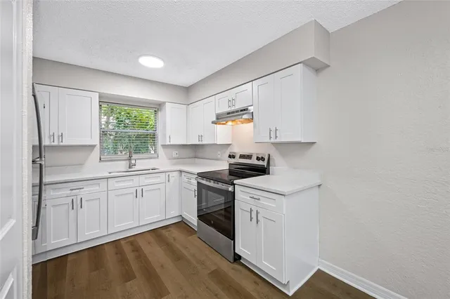 a kitchen with white cabinets appliances and a window