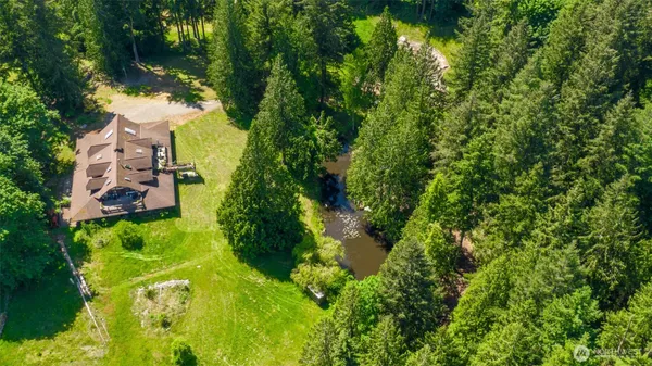 an aerial view of a house with pool yard outdoor and trees all around