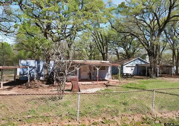 a view of a backyard with large trees and wooden fence