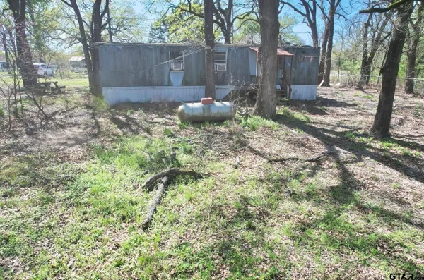 a backyard of a house with large trees and a wooden fence