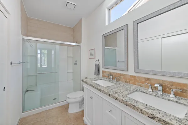 a bathroom with a granite countertop sink a toilet and shower