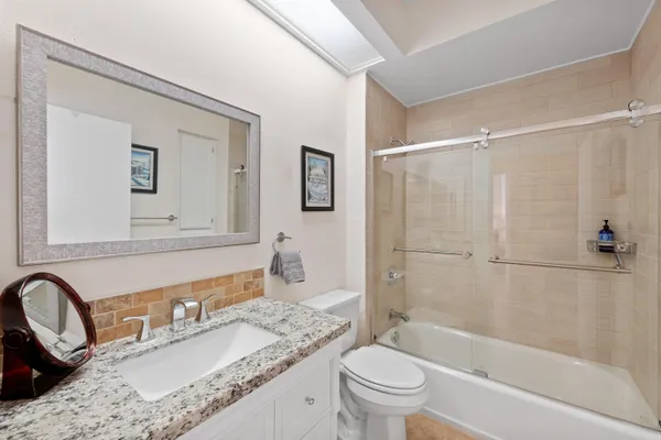 a bathroom with a granite countertop sink toilet and shower