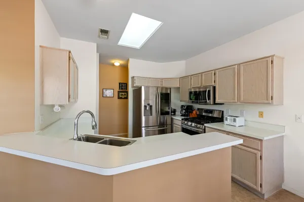 a kitchen with stainless steel appliances a sink a stove a microwave a refrigerator a counter top space and cabinets