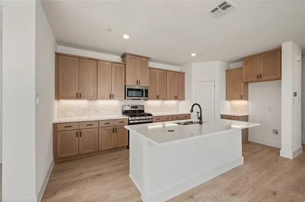 a kitchen with stainless steel appliances a sink stove top oven and cabinets