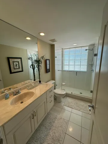 a spacious bathroom with a granite countertop sink a toilet and a mirror
