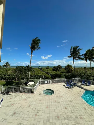 a view of swimming pool with seating area and trees in the background
