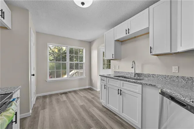 a kitchen with granite countertop a sink stove and cabinets