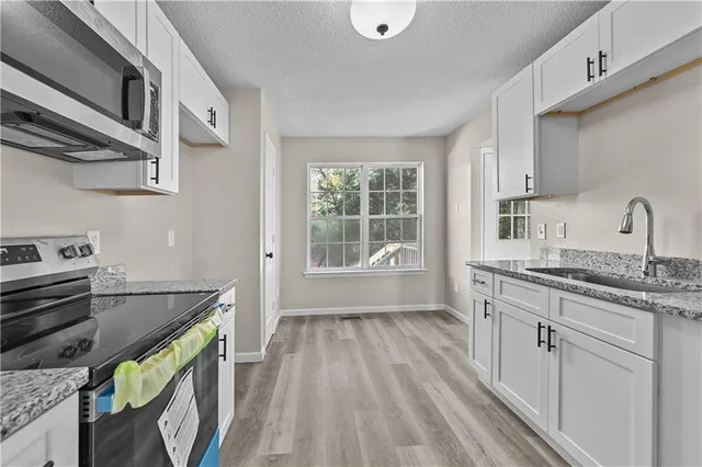 a kitchen that has a sink a stove and wooden floor