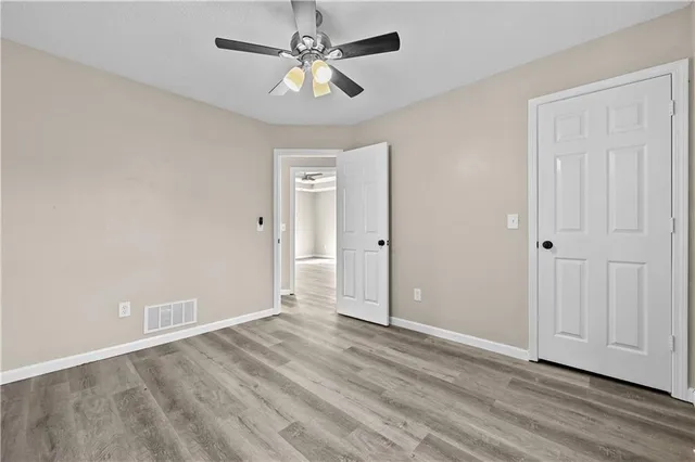 an empty room with wooden floor and ceiling fan