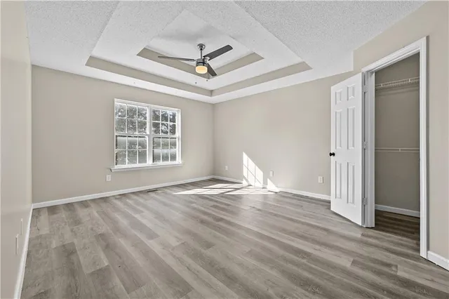 a view of empty room with wooden floor and fan