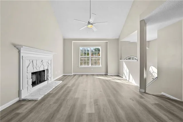 an empty room with wooden floor fireplace and windows