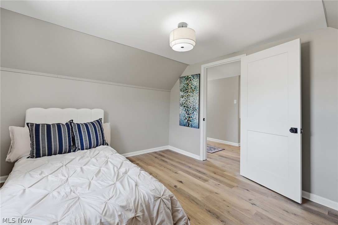 951 Bey Road Akron, OH 44312 - Photo 24 of 34 Second floor bedrooom featuring wood-finish flooring, a contemporary ceiling light fixture, a modern paneled door with matte black hardware, and light gray wall finishes