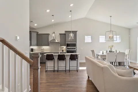 a living room with furniture kitchen and a wooden floor