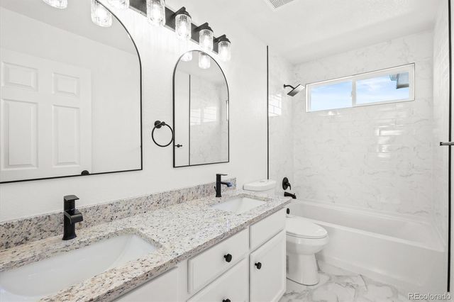 a bathroom with a granite countertop sink a toilet and a bathtub