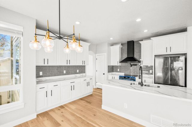 a kitchen with stainless steel appliances kitchen island granite countertop a sink a stove and a wooden floors