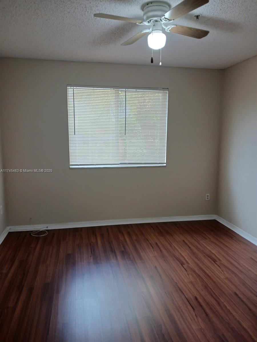 Pinehurst Club Condominiums Hollywood, FL 33021 - Photo 21 of 22 an empty room with wooden floor chandelier fan and windows