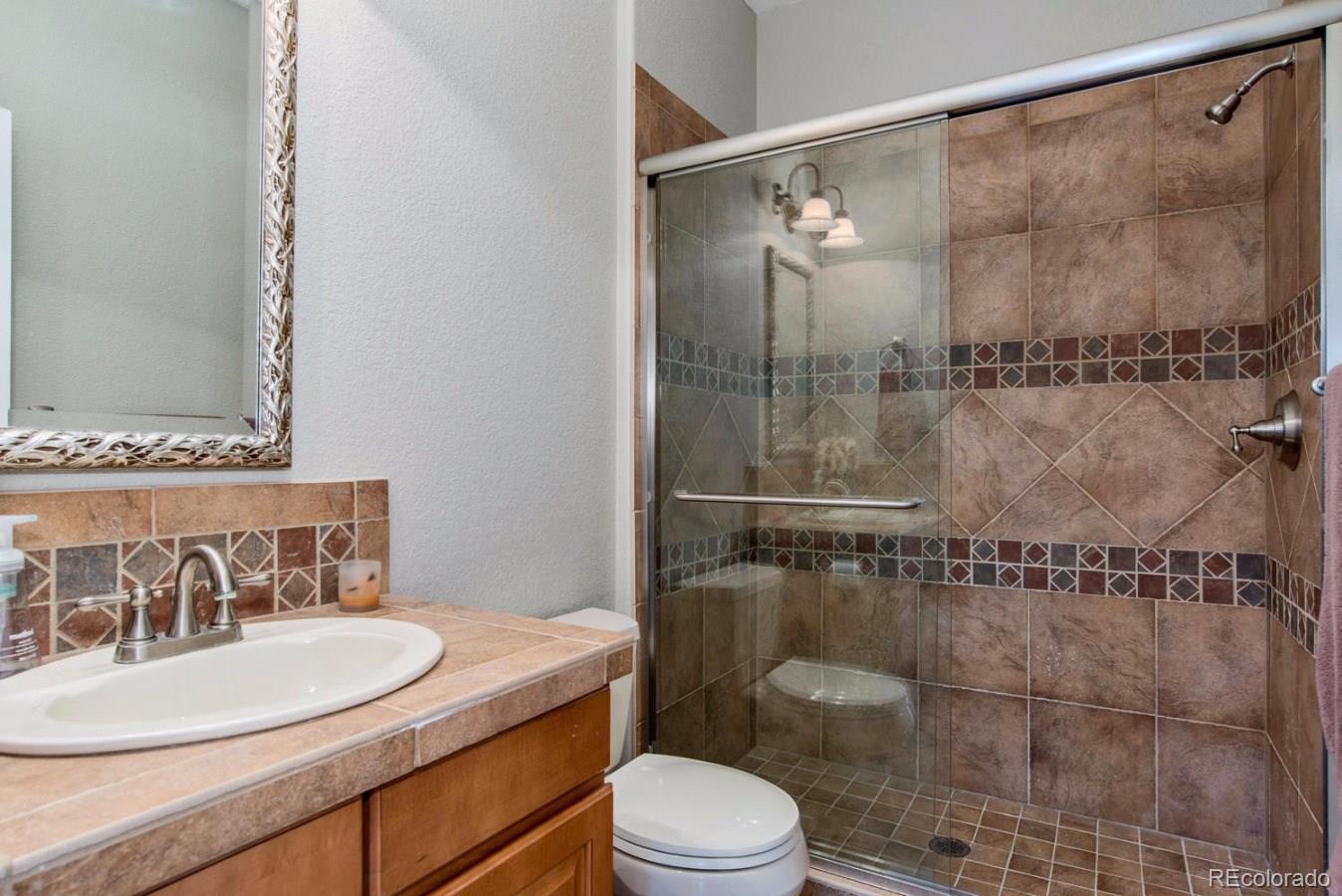 10685 Wynspire Road Highlands Ranch, CO 80130 - Photo 21 of 29 a bathroom with a sink toilet a mirror and shower