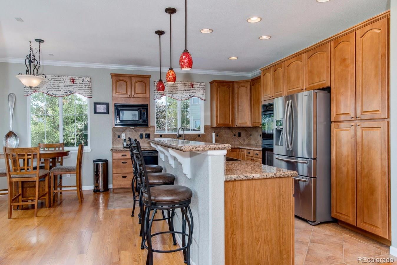 10685 Wynspire Road Highlands Ranch, CO 80130 - Photo 6 of 29 a kitchen with stainless steel appliances granite countertop a refrigerator a stove top oven a sink dishwasher a dining table and chairs with wooden floor