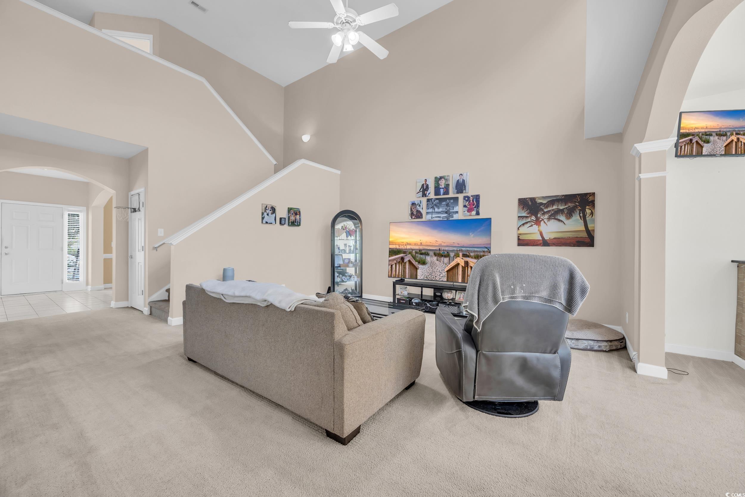 2352 Seneca Ridge Drive Myrtle Beach, SC 29579 - Photo 7 of 40 Living area with arched walkways, light colored carpet, stairs, a ceiling fan, and high vaulted ceiling