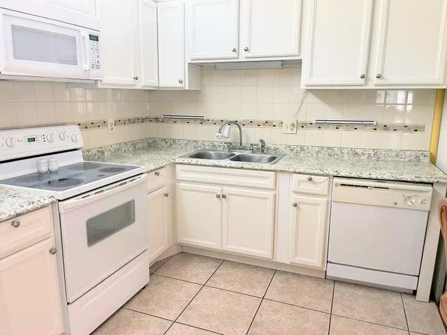 a kitchen with granite countertop white cabinets and white appliances