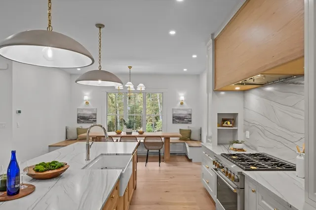 a kitchen with stainless steel appliances granite countertop a stove a sink a dining table and chairs with wooden floor