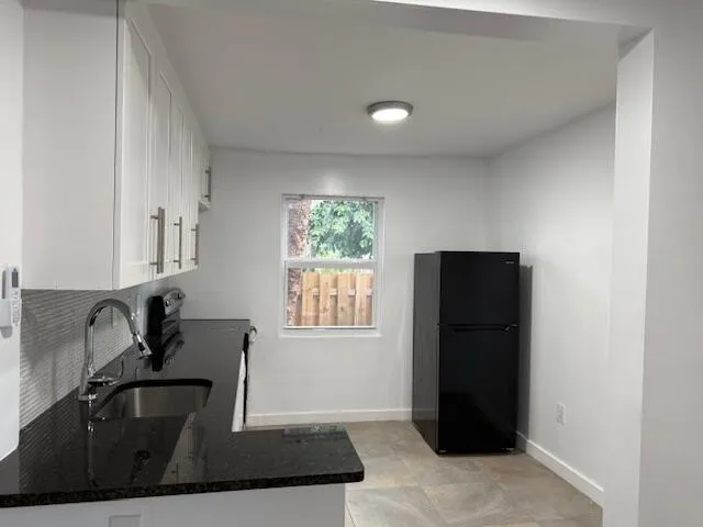 a kitchen with granite countertop a refrigerator and a sink