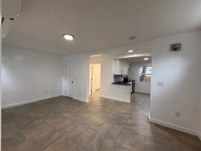 an empty room with a kitchen and a window