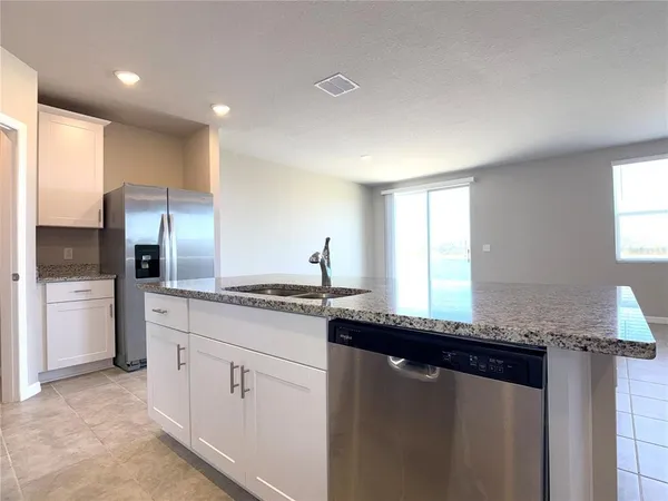a kitchen with granite countertop cabinets stainless steel appliances a sink and a window