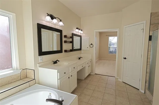 a bathroom with a double vanity sink mirror and bathtub