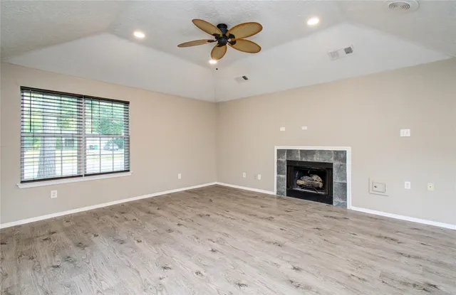 a view of an empty room and window with a chandelier fan