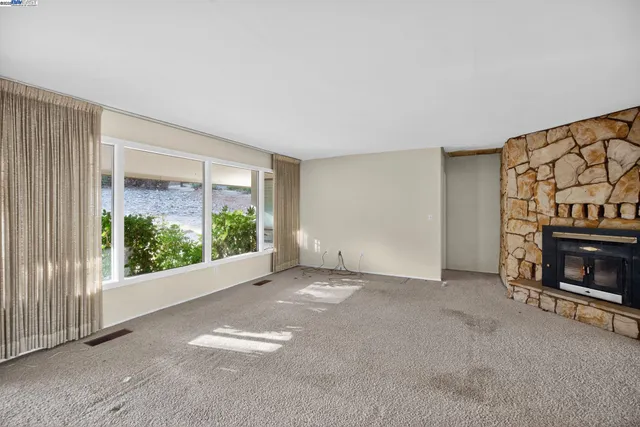 a view of an empty room with fireplace and a window