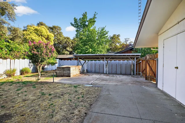 a view of a house with a yard and large tree
