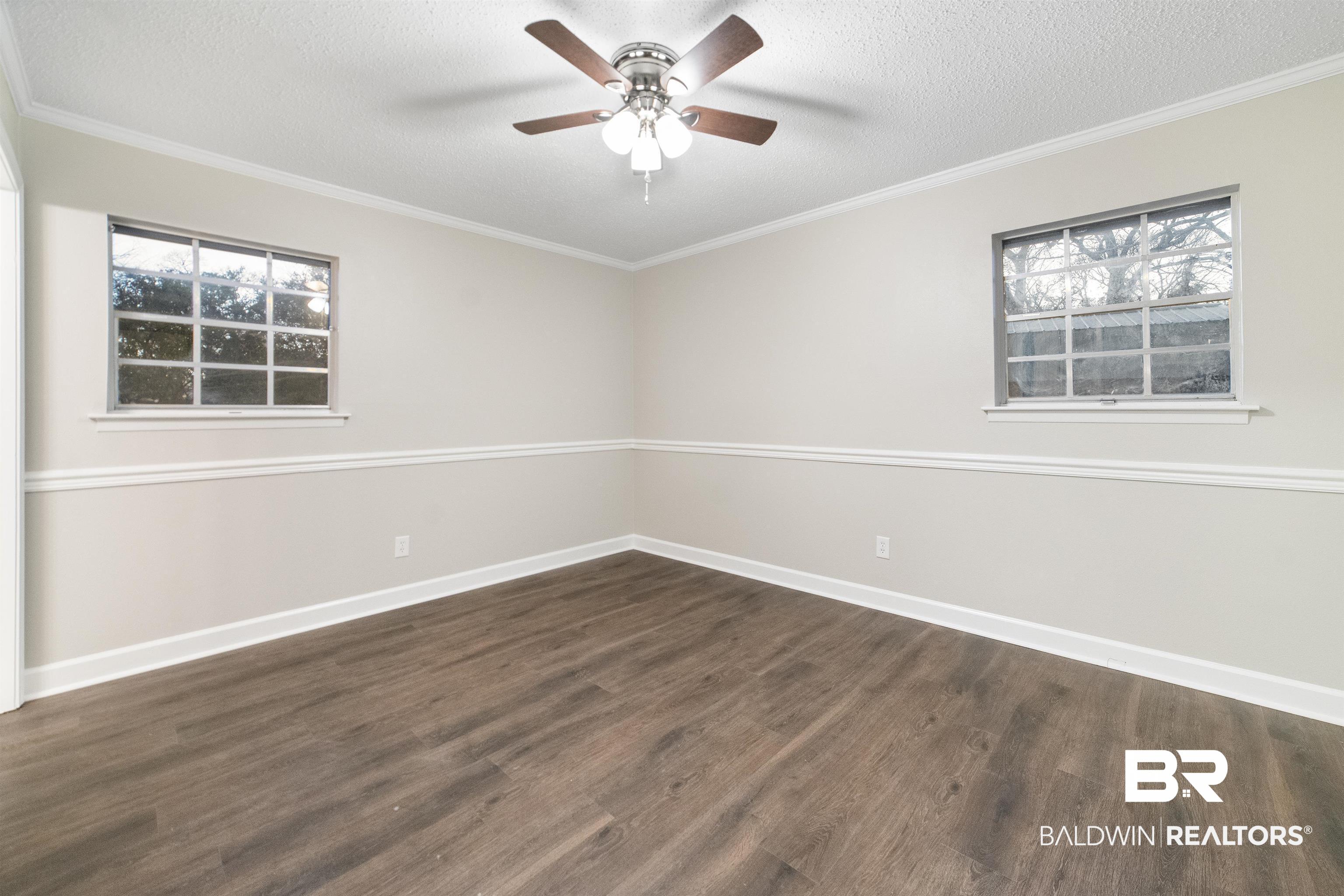 11833 Old Moffat Road Wilmer, AL 36587 - Photo 11 of 23 Spare room featuring a textured ceiling, dark wood-style flooring, a ceiling fan, baseboards, and ornamental molding