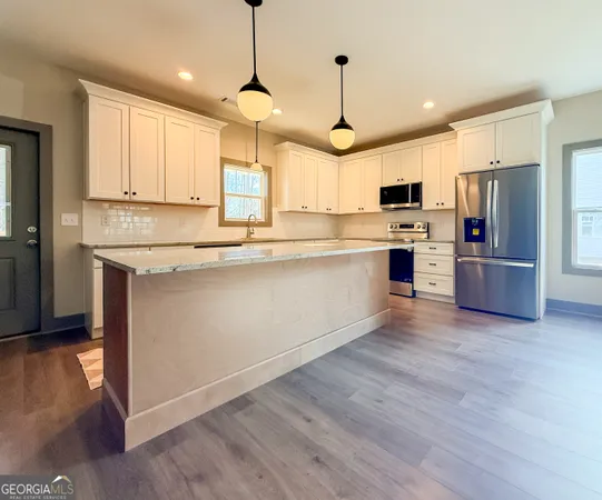 a kitchen with stainless steel appliances kitchen island granite countertop a sink a stove and a refrigerator