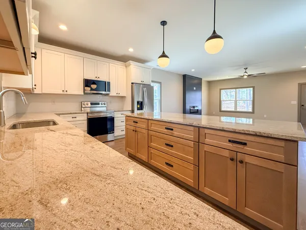 a kitchen with stainless steel appliances kitchen island granite countertop a sink a stove and cabinets