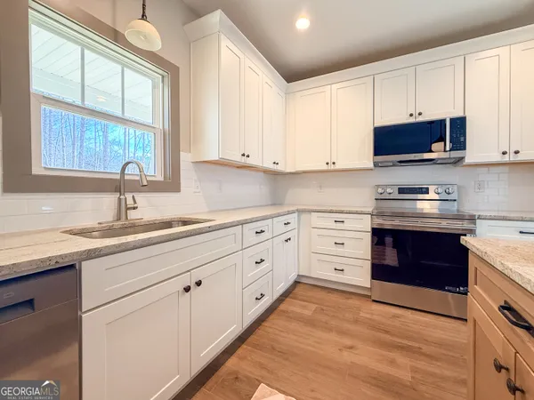 a kitchen with white cabinets sink and appliances
