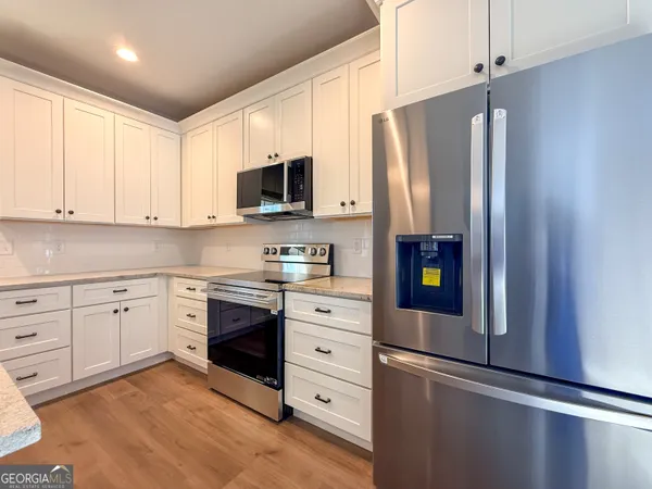 a kitchen with stainless steel appliances white cabinets a refrigerator and a stove
