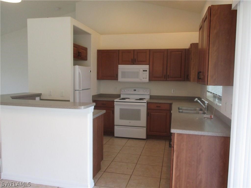 520 Raintree Street East Lehigh Acres, FL 33974 - Photo 12 of 18 a kitchen with a stove sink and a refrigerator