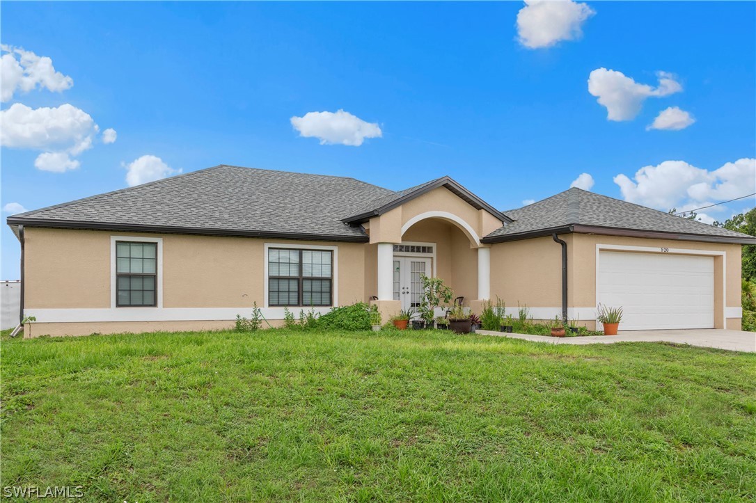 520 Raintree Street East Lehigh Acres, FL 33974 - Photo 2 of 18 a front view of a house with a yard and garage